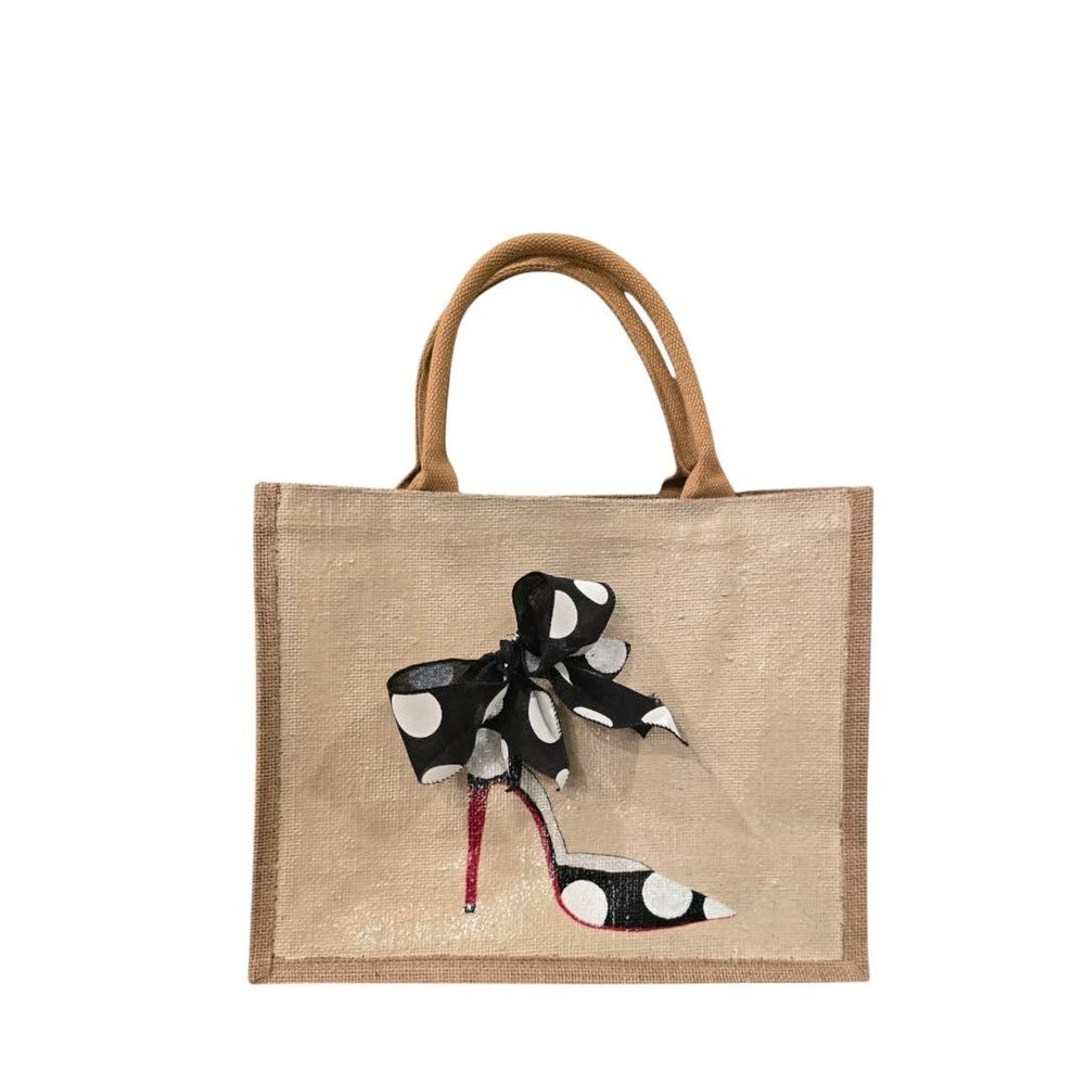 Beige burlap tote with brown handles, featuring a black polka-dot bow and a polka-dot high-heeled shoe with a red sole.