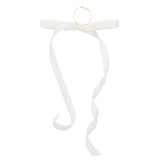 White velvet bow with a small gold ring charm at the top and curling ribbon tails.