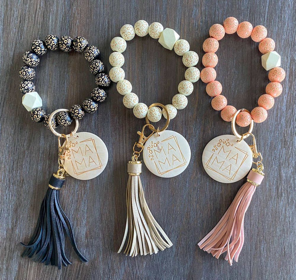 Three bead wristlets with round engraved discs; black, cream, and peach leopard beads with navy, beige, pink tassels.