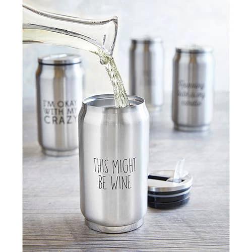 Shiny stainless steel can with THIS MIGHT BE WINE text, liquid pours into it from a glass carafe on a wooden surface.