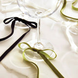 Green velvet bow wine charm tied around the stem of a wine glass; set of six.