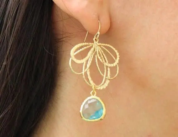 Gold-tone feather-inspired dangle earring with looping filigree and a pale blue aquamarine teardrop pendant.