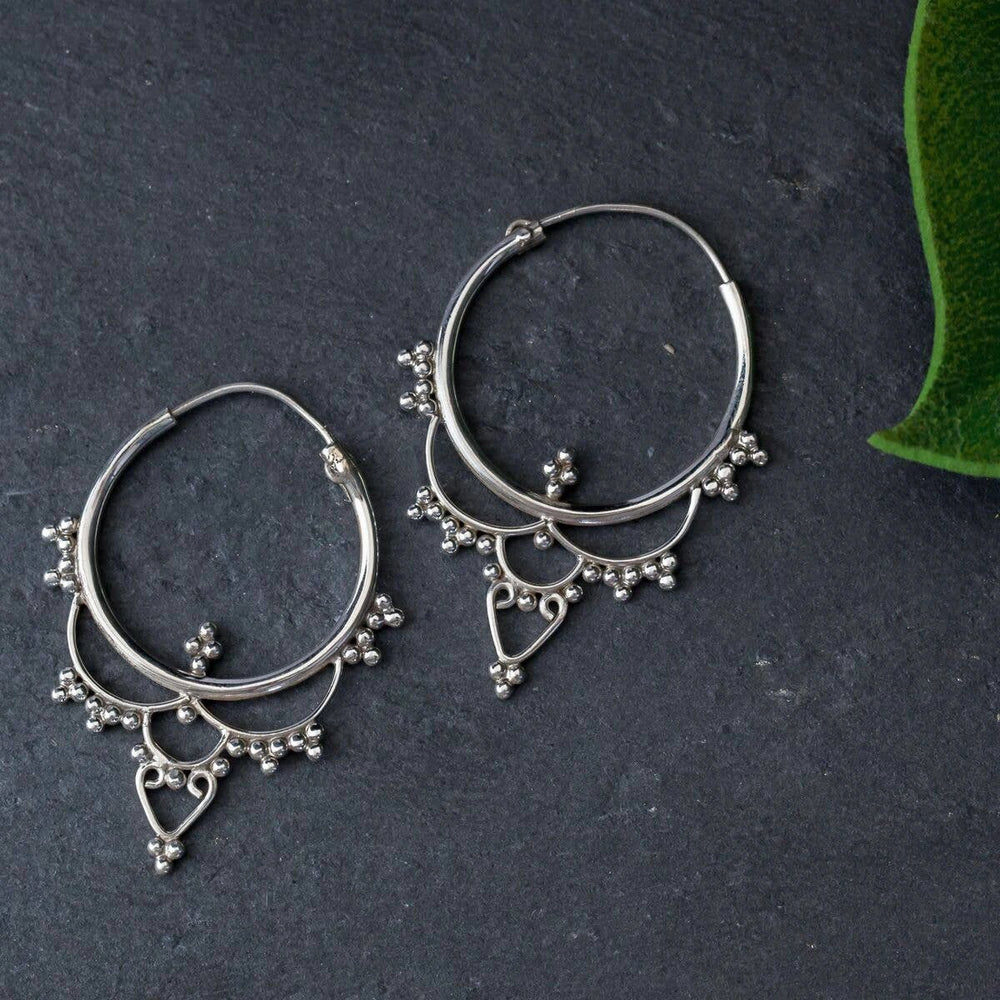 Pair of sterling silver Indian-inspired drop hoop earrings with beaded fringe and an open heart pendant.