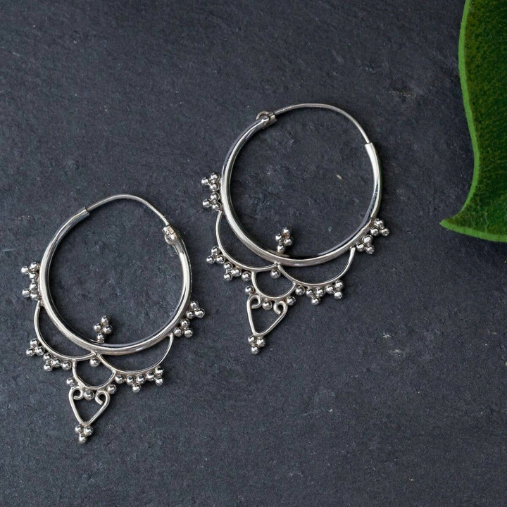 Pair of sterling silver Indian-inspired drop hoop earrings with beaded fringe and an open heart pendant.