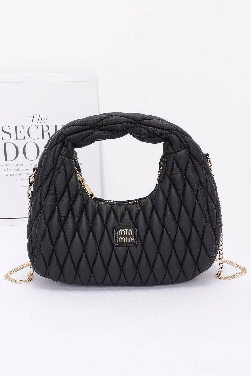 Black quilted leather hobo bag with diamond stitching, rounded top handle and gold chain strap, front logo plaque.