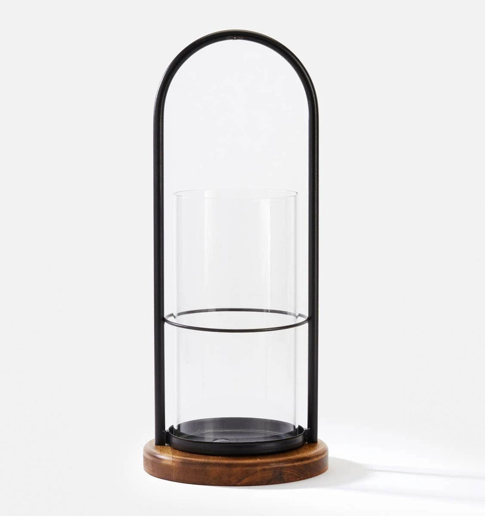 Large iron and wood hurricane candle holder with an arched black frame around a clear glass cylinder on a round base.