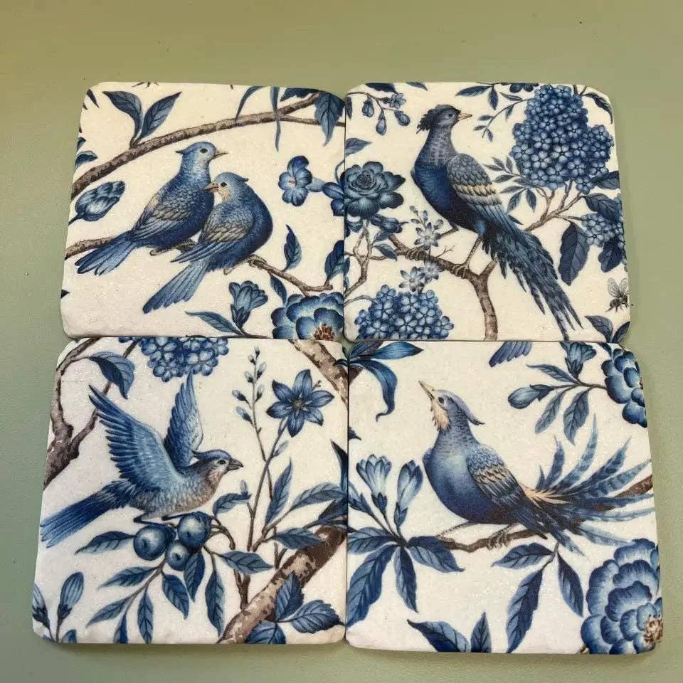Set of four square resin coasters with blue birds among branches and flowers on a cream background, rounded corners.