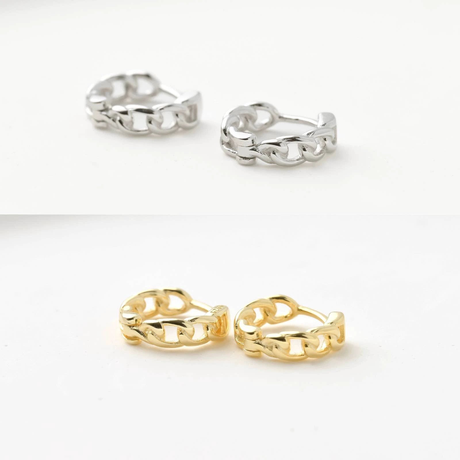 Silver and gold-tone curb-link huggie earrings, chunky chain-link hoops resting on a white background