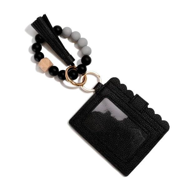 Beaded bracelet with black/gray beads, wooden cube, tassel, connected to a black vegan leather wallet.