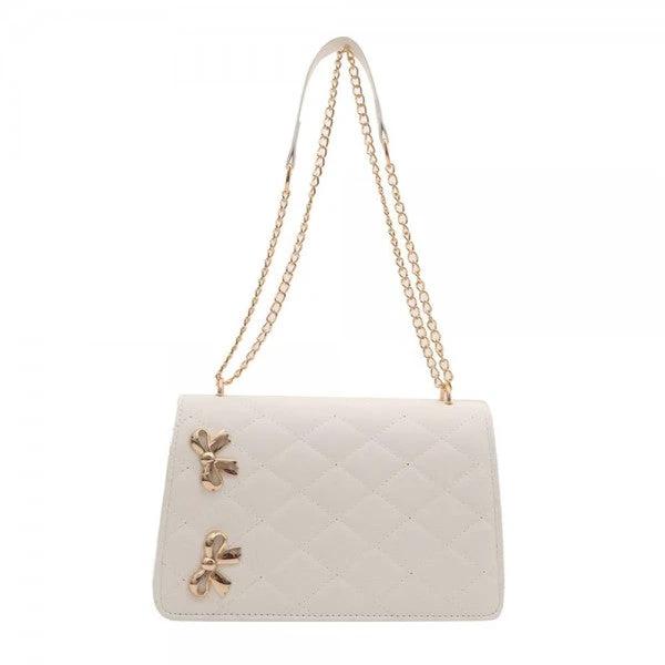 Cream vegan leather quilted crossbody tote with gold-tone chain strap and two bow-shaped metal accents on the front.