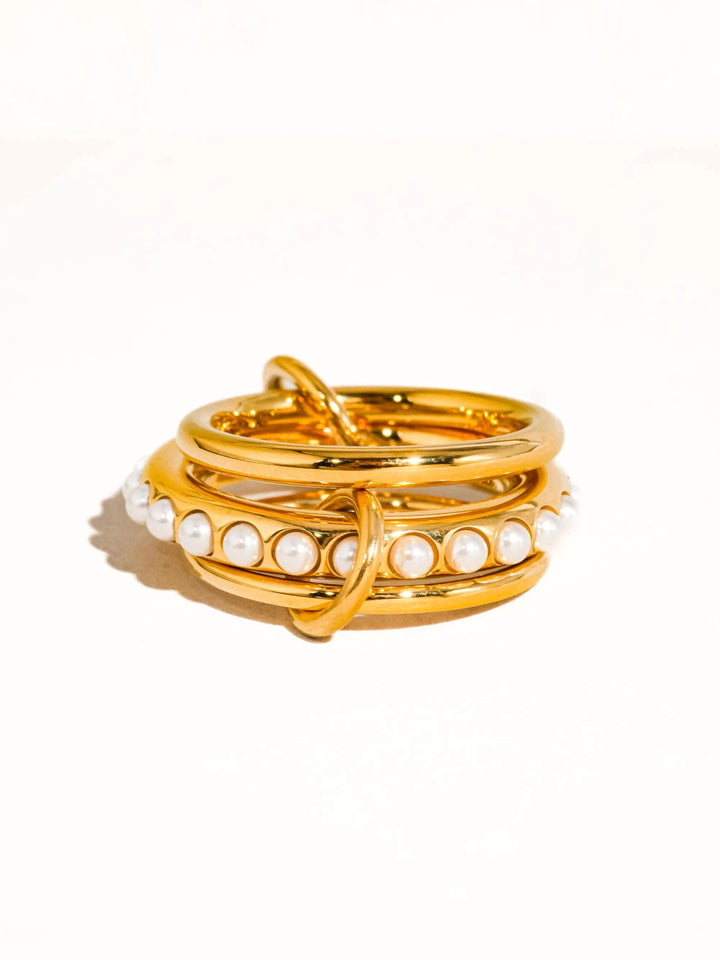 Stacked 18K gold rings featuring a pearl-embellished band with evenly spaced white pearls around the circumference.