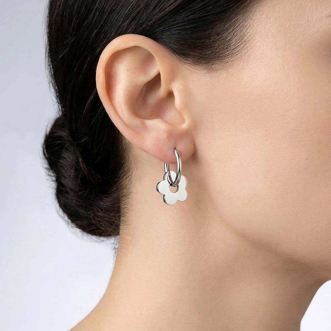 Small silver hoop earring with a white four-petaled flower charm hanging from the hoop.