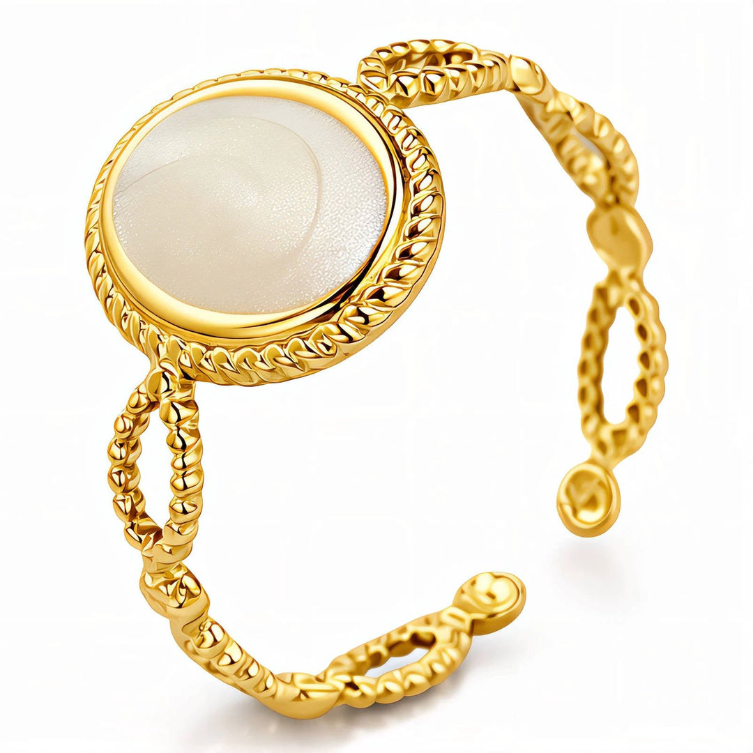 Gold-plated ring with a round nacre centerpiece in a braided rope bezel; open-ended band with small bead-ended tips.