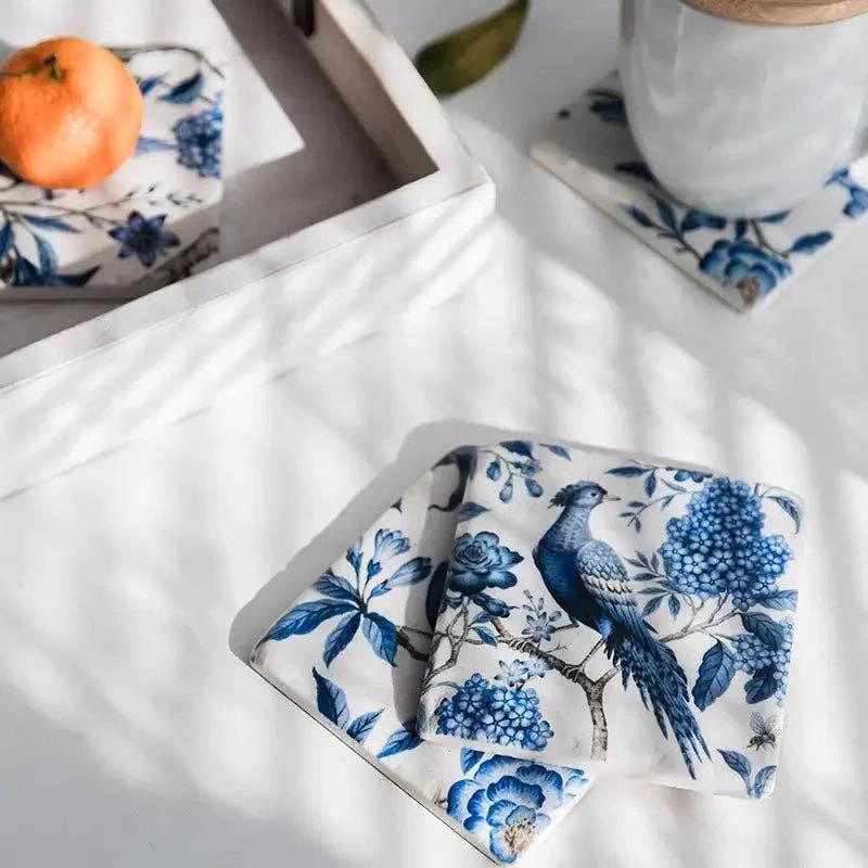 Set of four blue and white resin coasters featuring a perched bird among floral motifs.