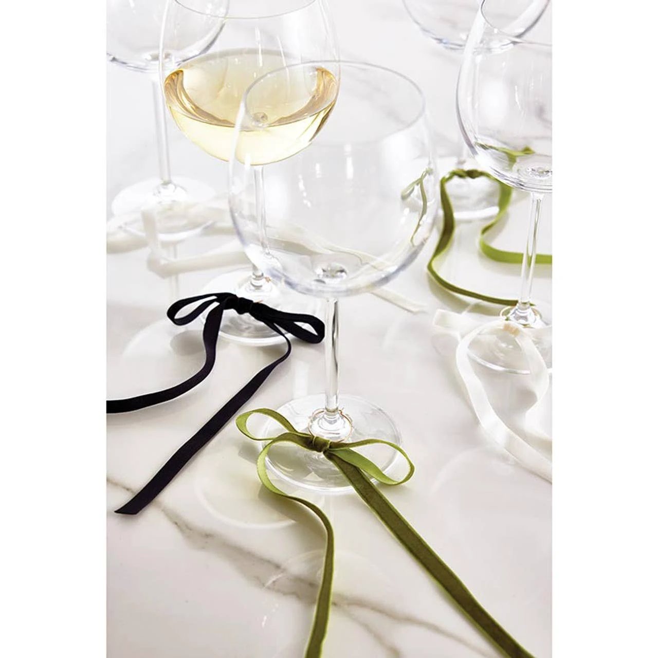 Green velvet bow wine charms tied around wine glass stems on a marble table; set of 6.