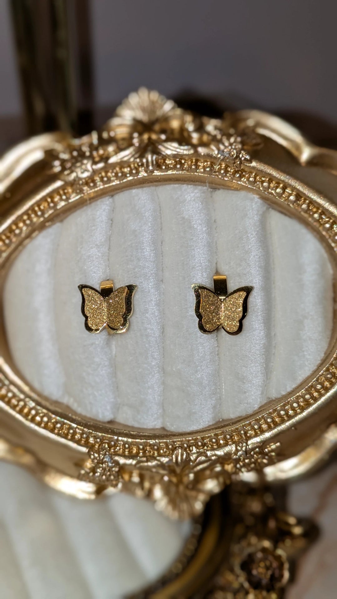 Butterfly hoop earrings, 18K gold-plated stainless steel, pair on ornate display.