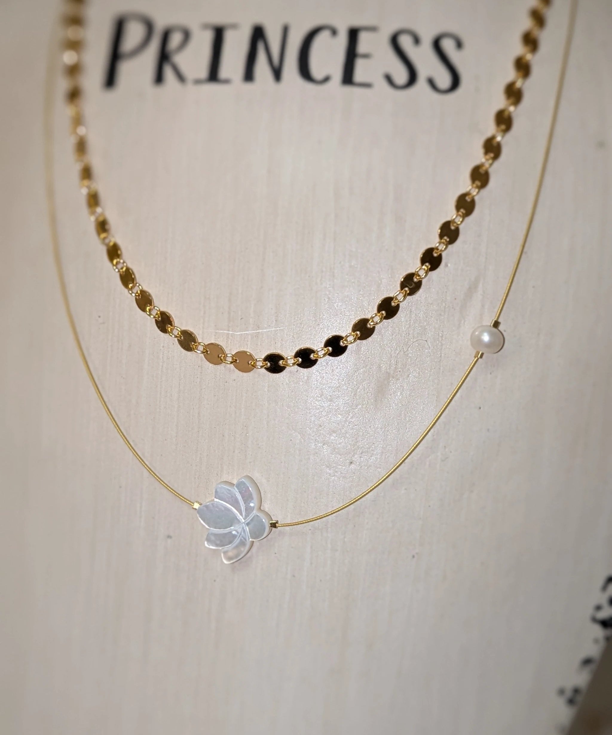 The White Lotus Necklace by Mar&Ella; two-layer gold-tone necklace with a white lotus charm and a pearl bead.