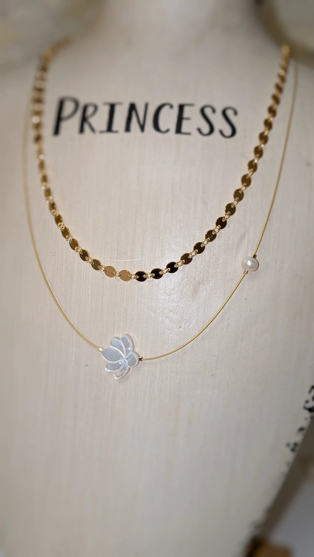 The White Lotus Necklace by Mar&amp;Ella; two-layer gold-tone necklace with a white lotus charm and a pearl bead.