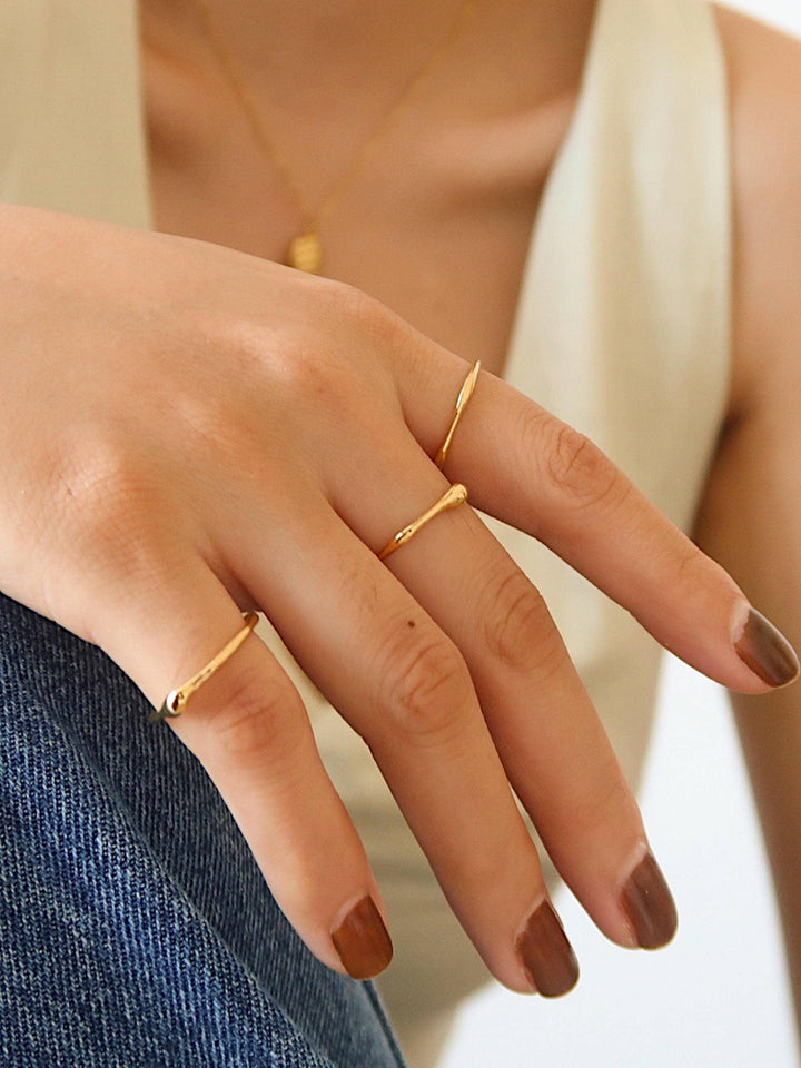 Two thin yellow-gold minimalist band rings with curved ends worn on a model&