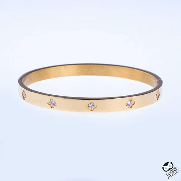 Yellow gold plated bangle with evenly spaced tiny flower-shaped crystal studs around the band.