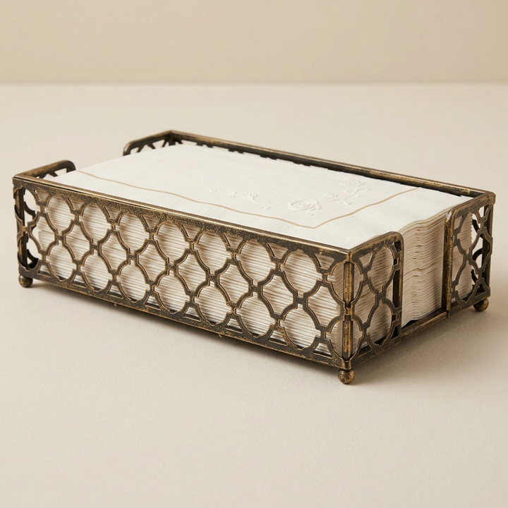 Antique brass trellis caddy with decorative ivory napkins on a plain ivory background