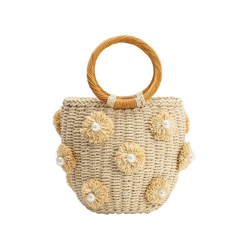 Beige woven straw tote with a circular braided handle and added flower-shaped rosettes each with a pearl center.
