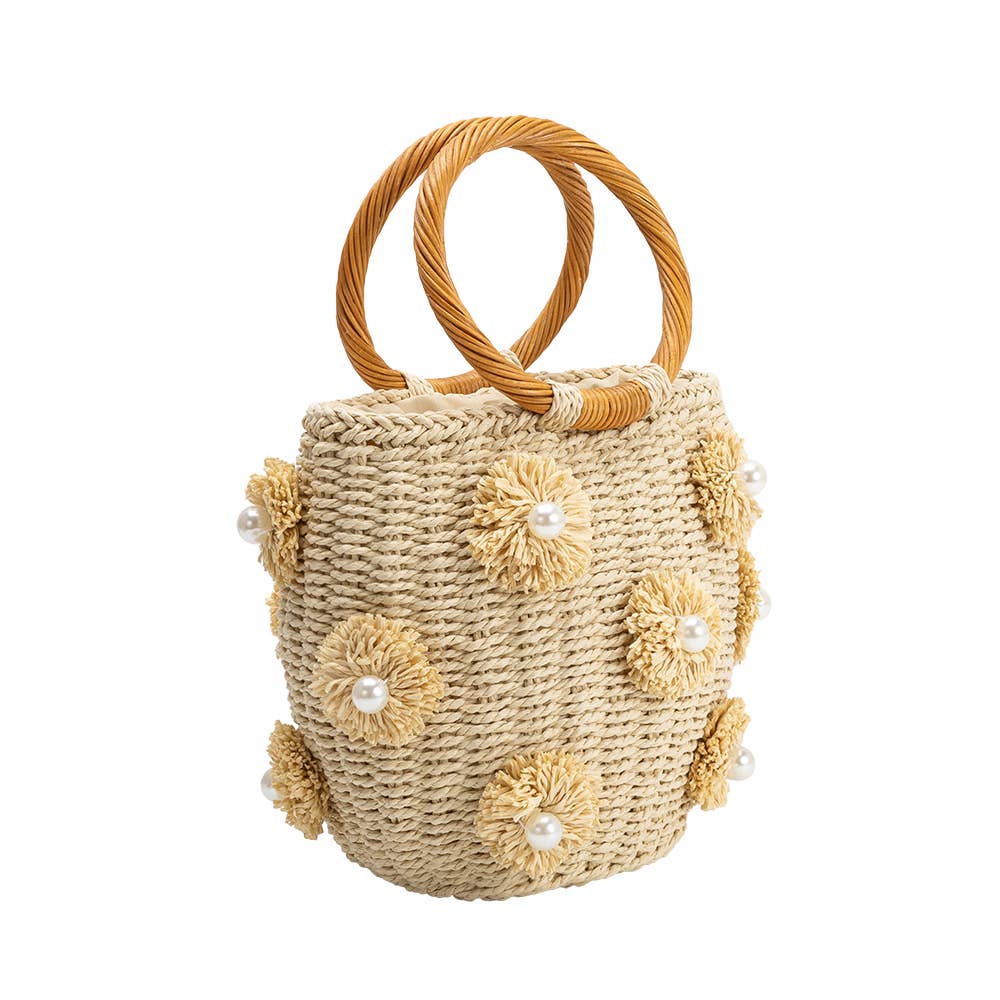 Natural straw tote with two round braided handles, adorned with cream yarn flower appliques with pearl centers.