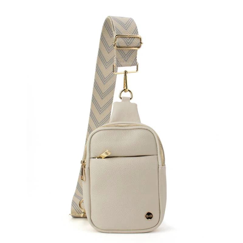Beige pebbled sling bag with front zip pocket, gold hardware, and a wide beige-blue chevron-pattern strap.