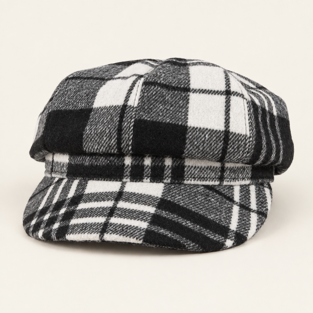 Black, gray and white tartan plaid newsboy cap on an off-white background