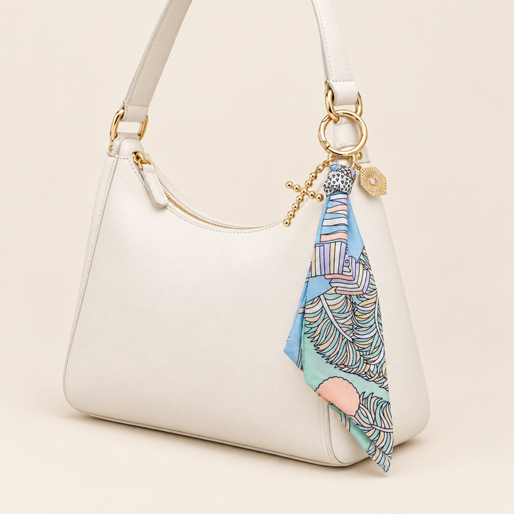 Louisa pastel scarf bag charm on a white shoulder bag