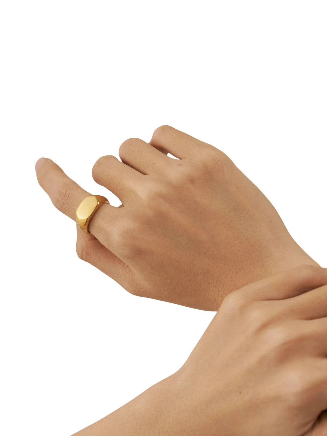 Close-up of a polished yellow-gold hexagon signet ring worn on a finger.