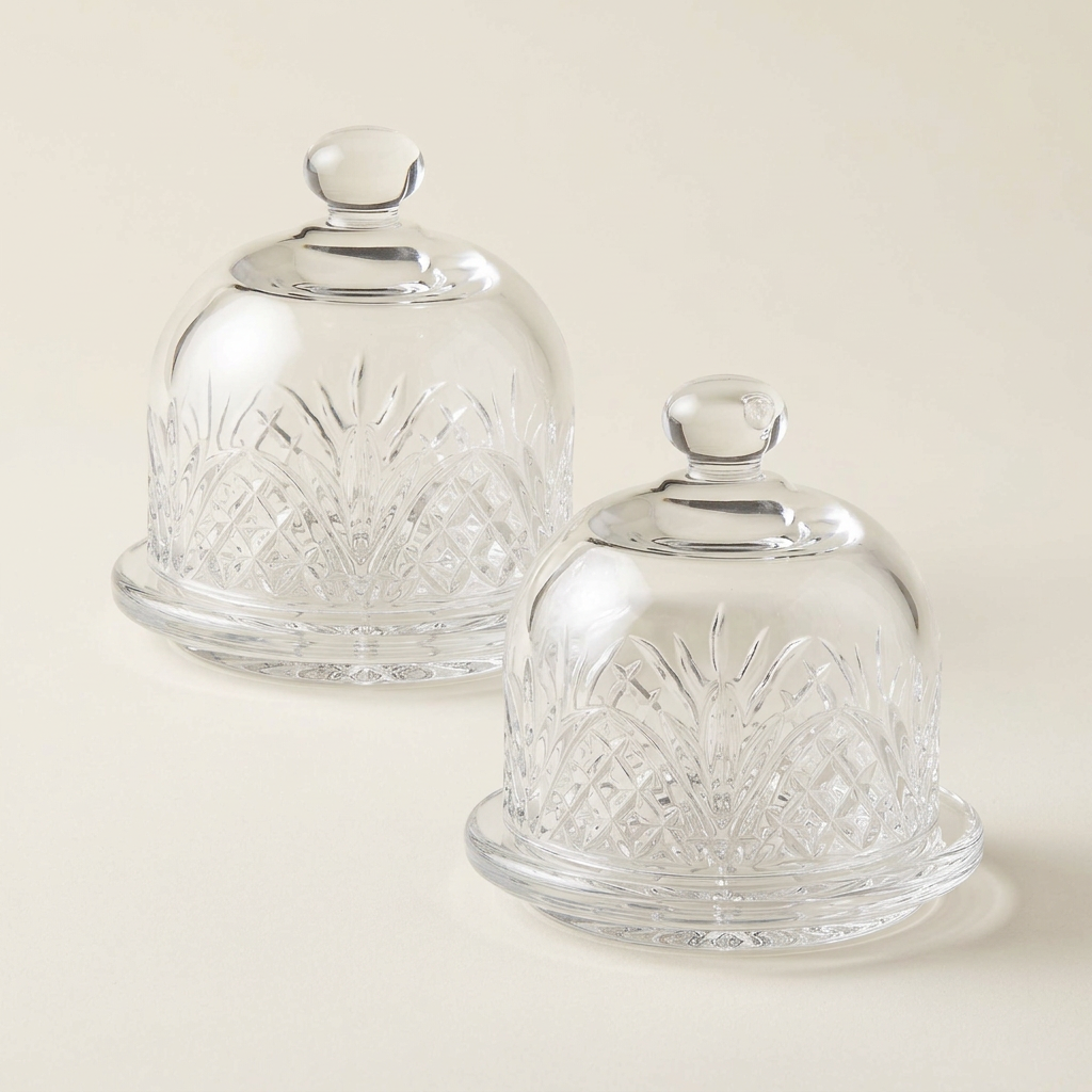Pair of clear cut-glass mini butter dishes on a plain ivory background