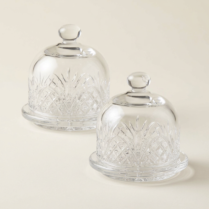 Pair of clear cut-glass mini butter dishes on a plain ivory background