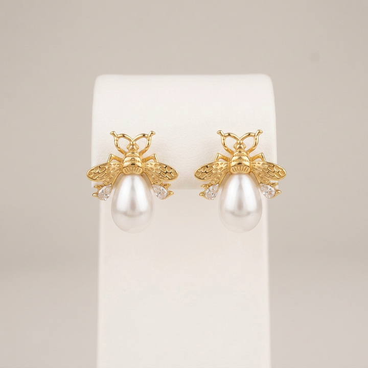 Three-quarter-inch pearl bee earrings on a white stand