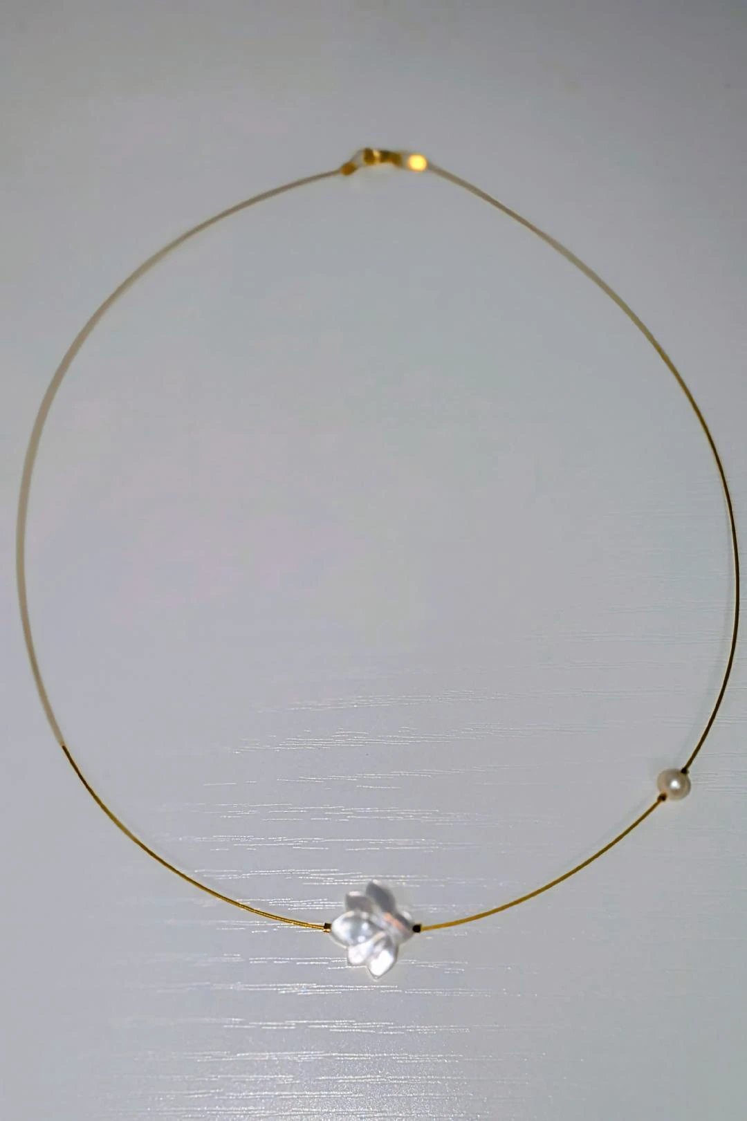 The White Lotus Necklace: delicate gold-tone wire choker with a white lotus flower charm and a pearl bead