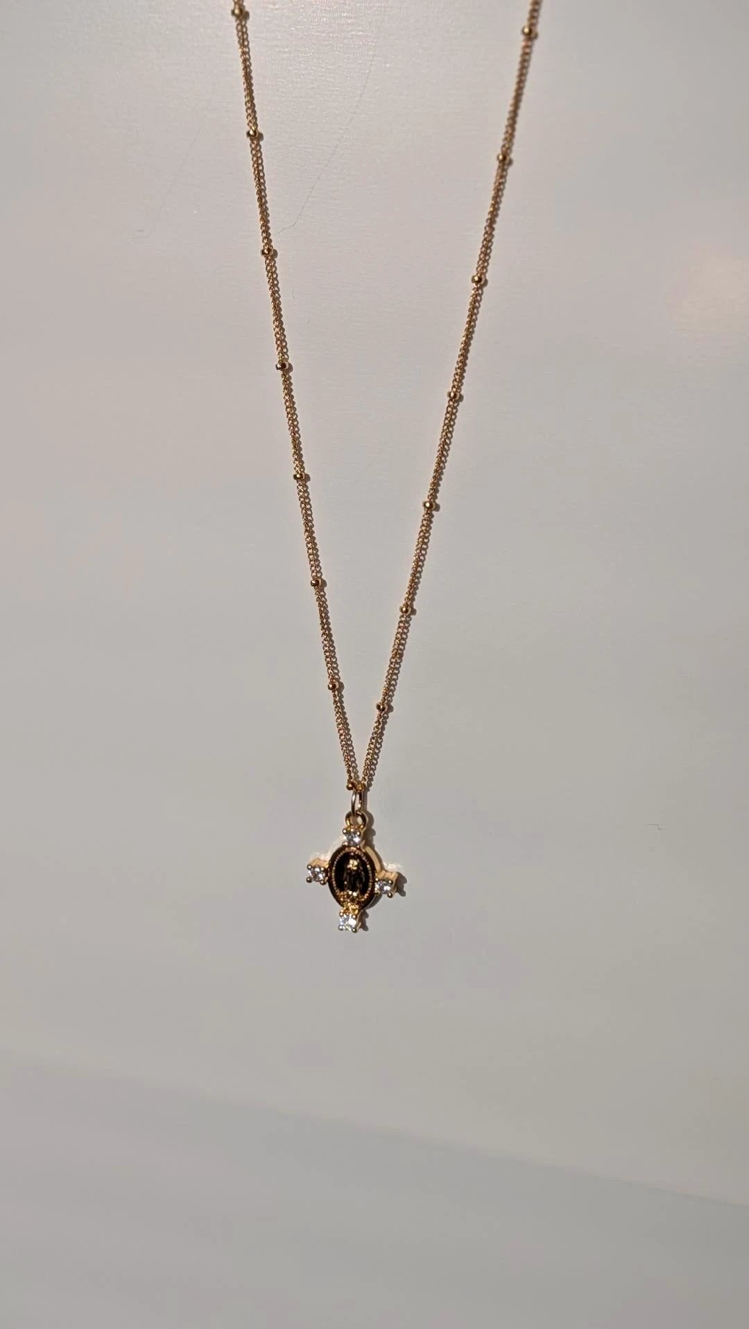 Camila Cross Necklace; 14k gold chain with beaded links and a cross pendant featuring a dark center stone and clear accents