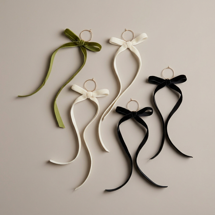 Velvet bow wine charms by themselves on a plain warm greige background